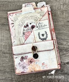 an old book with flowers on it and some tags attached to the front cover, sitting on a wooden surface