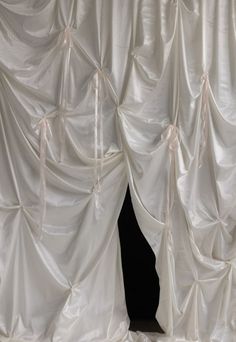 an open curtain with white satin drapes