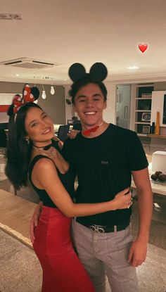 a man standing next to a woman wearing minnie mouse ears