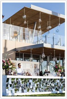 a man standing in front of a bar with lots of wine glasses hanging from the roof