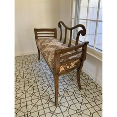 a wooden chair sitting on top of a tiled floor next to a window with curtains