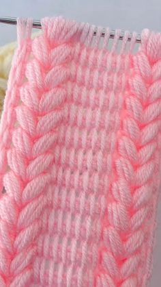 a pink crochet blanket sitting on top of a white table next to a pair of scissors