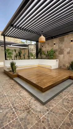 an outdoor area with wooden flooring and plants on the wall, in front of a building