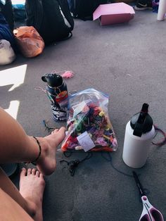 someone is sitting on the ground with their feet up next to a bag full of confetti