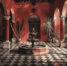 a red building with black and white checkered flooring in front of a fountain surrounded by potted plants