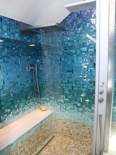 a shower with blue and brown tiles on the walls