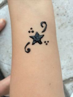 a small tattoo on the arm of a person with a star and swirls in it