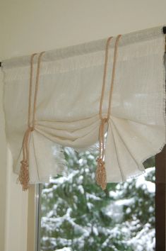 the curtains are hanging on the window sill in front of the snow covered trees