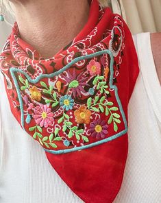 a woman wearing a red bandana with colorful flowers on the front and back of her neck