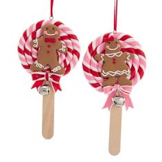 two lollipops decorated with gingerbread and candy canes are hanging from hooks