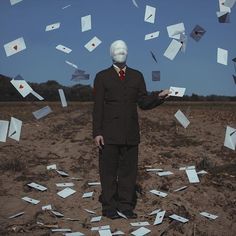 a man standing in the middle of a field with lots of papers flying around him