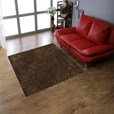 a living room with a red leather couch and wooden floors in front of a large window