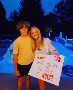 two people standing next to each other holding a sign