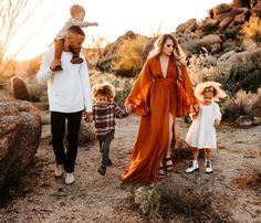 a family walking in the desert holding hands and smiling at the camera with their two children