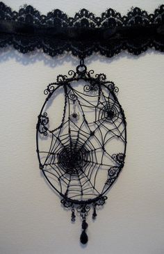 a spider web hanging on the wall next to a black lace choker with beads