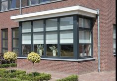 a brick building with several windows and plants in the front