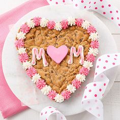 a heart shaped cookie decorated with pink and white icing on top of a plate