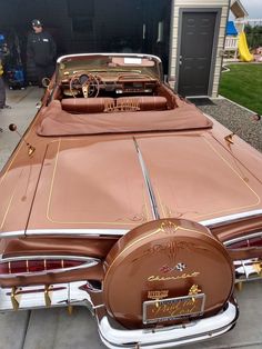 a brown and white car parked in front of a garage