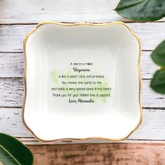 a white and gold plate with a poem on it next to some green leafy leaves