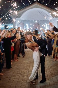 a bride and groom kiss as they are surrounded by sparklers at their wedding reception