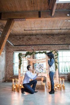 a man kneeling down next to a woman in a room with candles on the floor