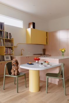 a dog sitting on a chair at a table in the middle of a kitchen with yellow cabinets