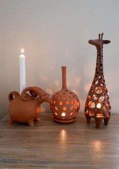 three ceramic animals and a lit candle on a table