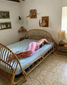 a woman laying on top of a blue bed in a room with pictures on the wall