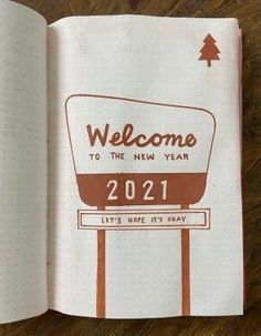 an open notebook with the words welcome to the new year written in brown on it