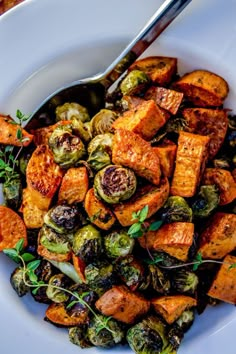 a white bowl filled with sweet potatoes and brussel sprouts