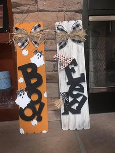 two wooden signs with the word boo on them are hanging from a string in front of a fireplace