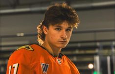 a young man in an orange jersey is looking at the camera