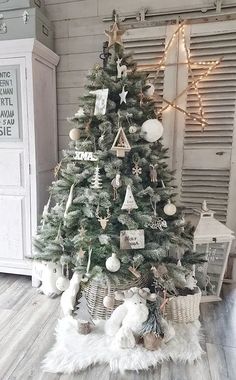 a small christmas tree in a room with white fur rugs and lights on the wall