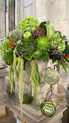 a vase filled with lots of different types of flowers and greenery on top of a table