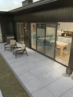 an outdoor patio with chairs and tables next to the house's sliding glass doors