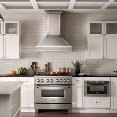 a stove top oven sitting inside of a kitchen next to white cabinets and counter tops