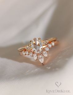 a close up view of a diamond ring on a white cloth with the word love written below it