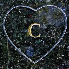 a heart shaped object with the letter c in it's center surrounded by snow