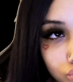 a close up of a person with makeup and piercings on her nose, looking at the camera