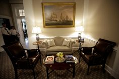 a living room filled with furniture and a painting on the wall above it's doorway