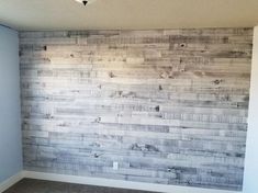 an empty room with wood planks on the wall and carpeted flooring in front of it