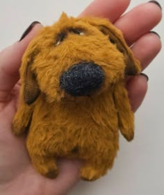 a hand holding a small yellow dog toy