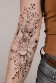 a woman's arm with flowers and leaves tattooed on the side of her arm