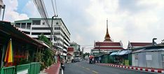 an empty street with people riding motorcycles on the side and buildings in the back ground