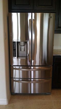 a stainless steel refrigerator in a kitchen with black cabinets