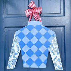 a blue and white checkered shirt with a red bow hanging on the front door