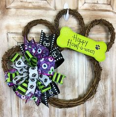 a mickey mouse wreath with a dog bone on it and a happy halloween tag hanging from the front door