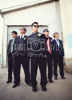 a group of men standing next to each other in front of a garage door wearing sunglasses