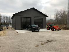 two large trucks parked in front of a building with a tractor on the lot next to it