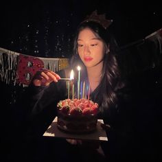 a woman is blowing out candles on her birthday cake while holding a cell phone in front of her